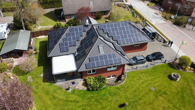 Ein modernes Haus mit Solarpanelen auf dem Dach und gepflegtem Garten.